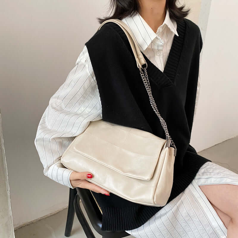 Fashionable PU Leather Small Square Bag for Women in beige carried by a model wearing a black vest over a white shirt.
