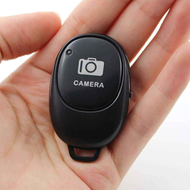 Bluetooth selfie remote for Android iOS in a hand, compact design for easy photography.