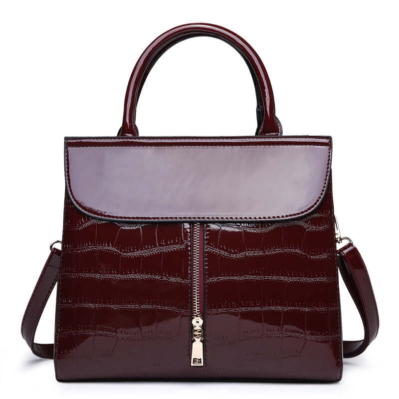 Fashionable shoulder crossbody tote bag for women in glossy burgundy with stylish zippers and dual handles.