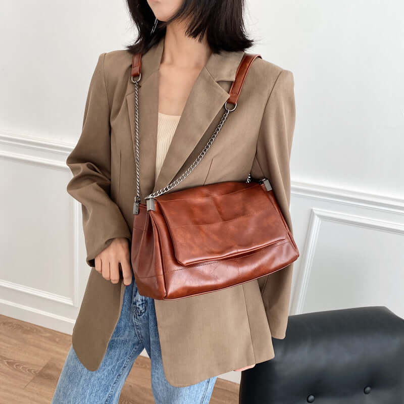 Fashionable woman wearing a trendy PU leather small square bag in coffee color with a stylish blazer.