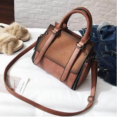 Faux suede bucket bag with stylish design, featuring dual handles and a detachable shoulder strap on a white background.