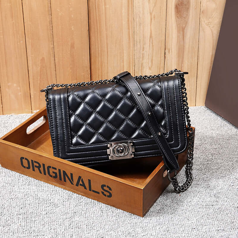 Stylish chain shoulder bag displayed on a wooden tray, featuring a quilted design and a sleek chain strap.