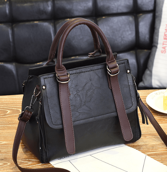 Faux suede bucket bag in black with brown straps on a wooden table, stylish and functional design.