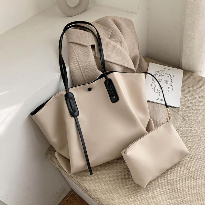Women's one shoulder handbag in chic beige with stylish black handles and matching small pouch.