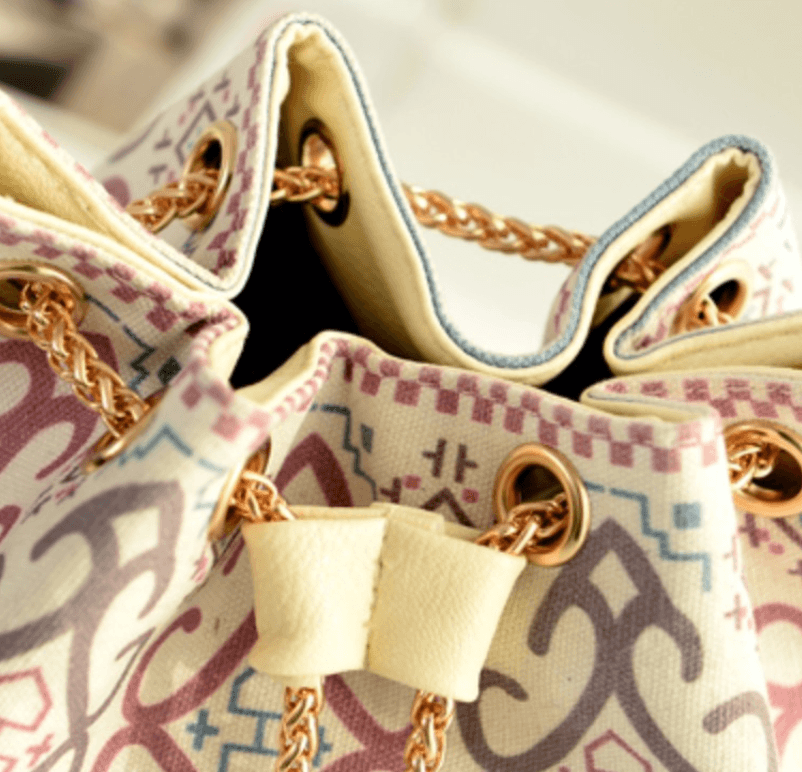 Close-up view of ethnic style canvas bucket bag showcasing unique patterns and gold chain details.