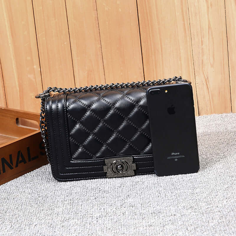 Stylish chain shoulder bag in black PU fabric beside an iPhone, showcasing its elegant design and functionality.