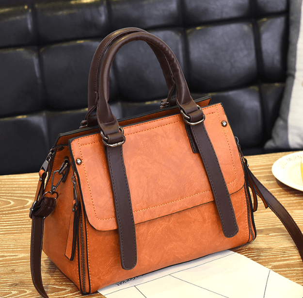 Faux suede bucket bag in orange with brown straps, perfect for style and functionality.