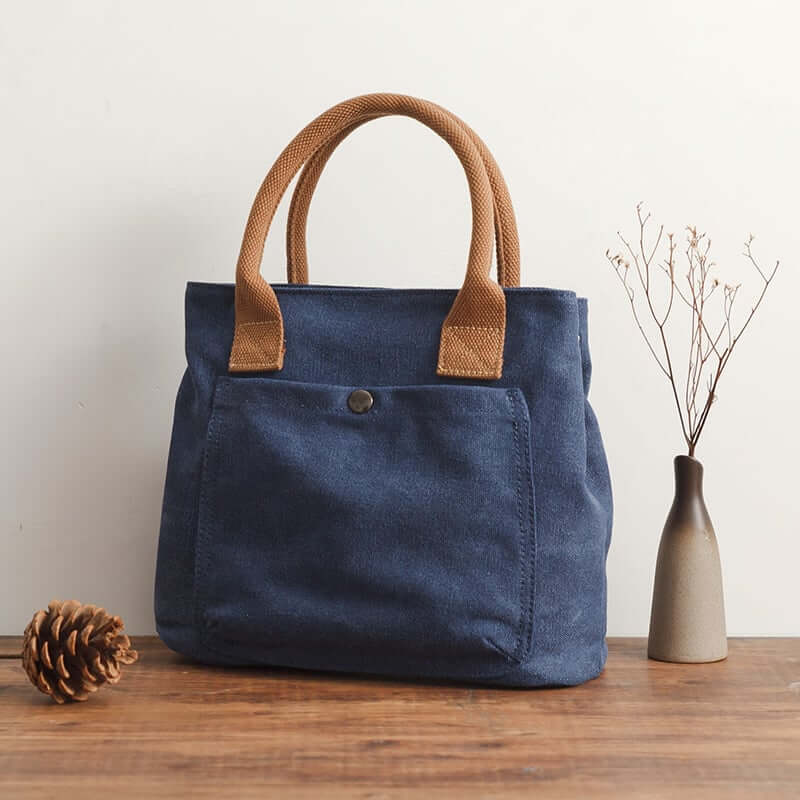 Japanese and Korean Women's Fashion Handbag in navy blue with brown straps on a wooden table.