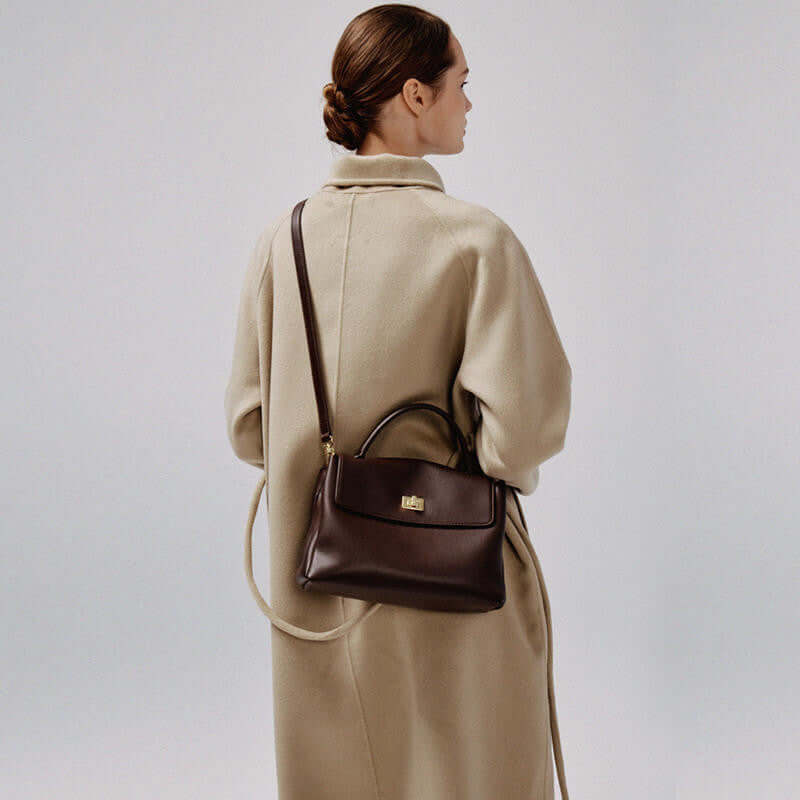 Large capacity cowhide crossbody bag displayed on a woman wearing a beige coat.