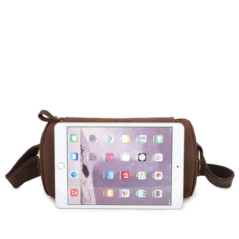Leather crossbody messenger bag with tablet on top, showcasing its sleek design and practical use.