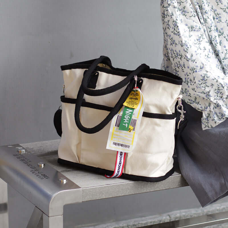 Stylish shoulder tote bag placed on a metal surface, showcasing its urban design and functional features.