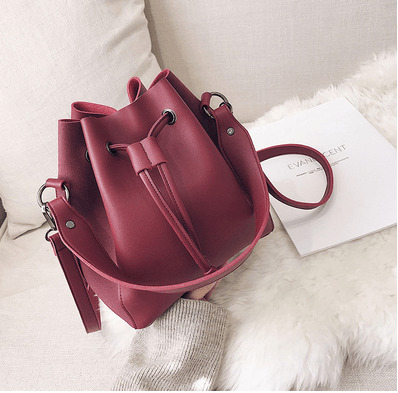 Stylish bucket bag in burgundy color with adjustable strap, perfect for urban chic looks.