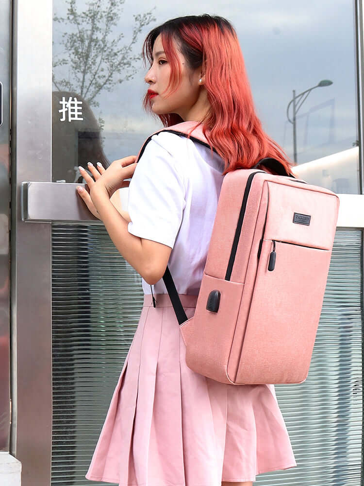 Stylish woman carrying a pink Men's Casual Travel Laptop Backpack Daypack near a modern building entrance.